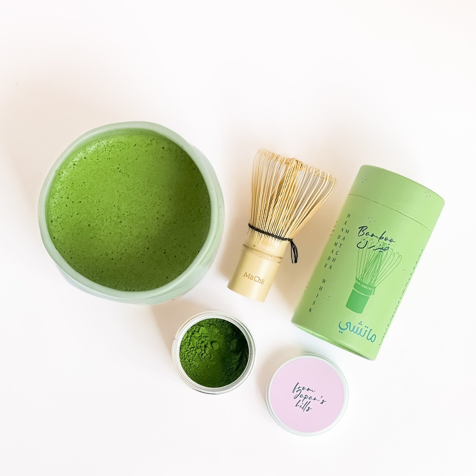 a bowl of matcha filled to the top. a bamboo whisk and an opened matcha tin next to it.