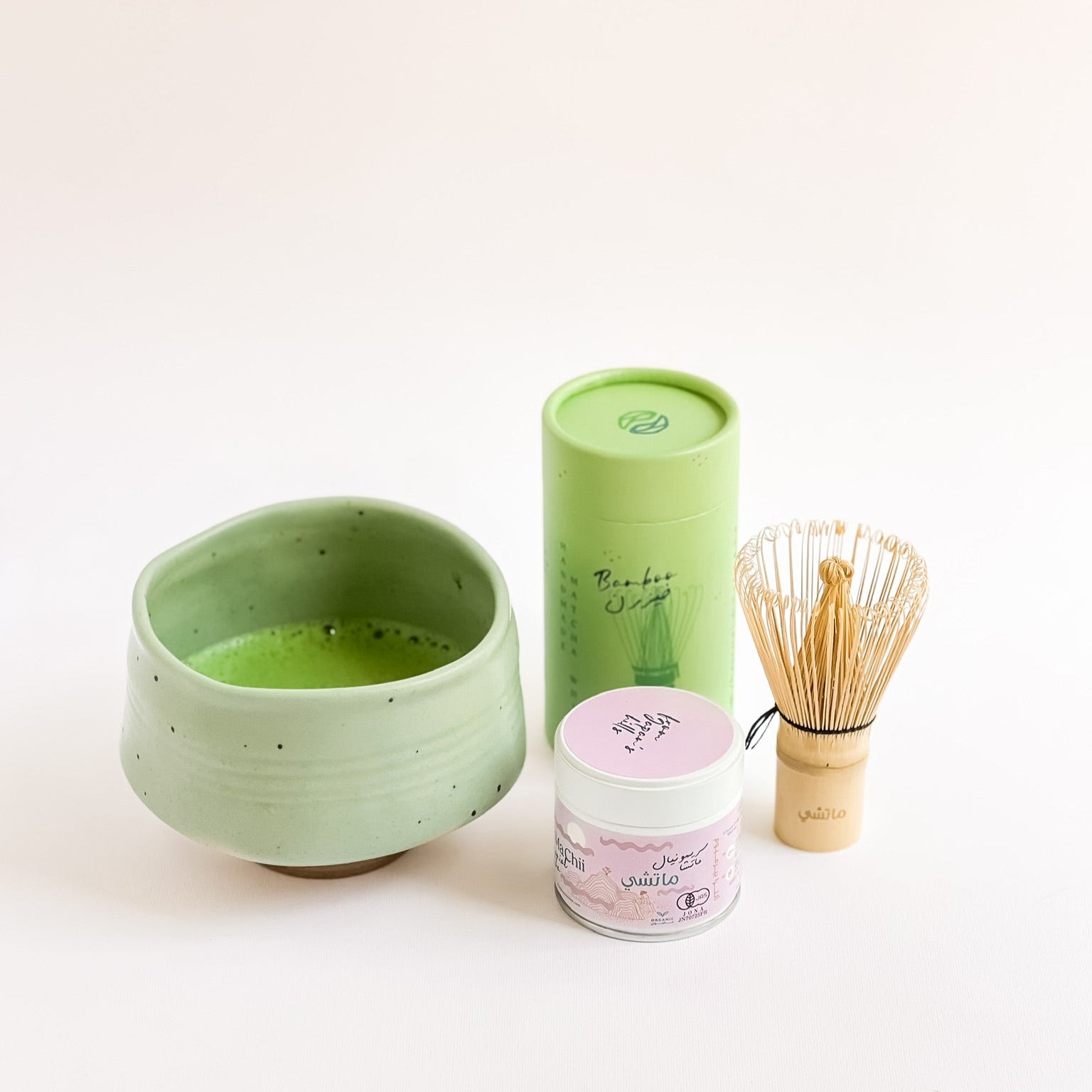 matcha bowl with a bamboo whisk and a ceremonial match tin next to it. The bowl is full of matcha tea.