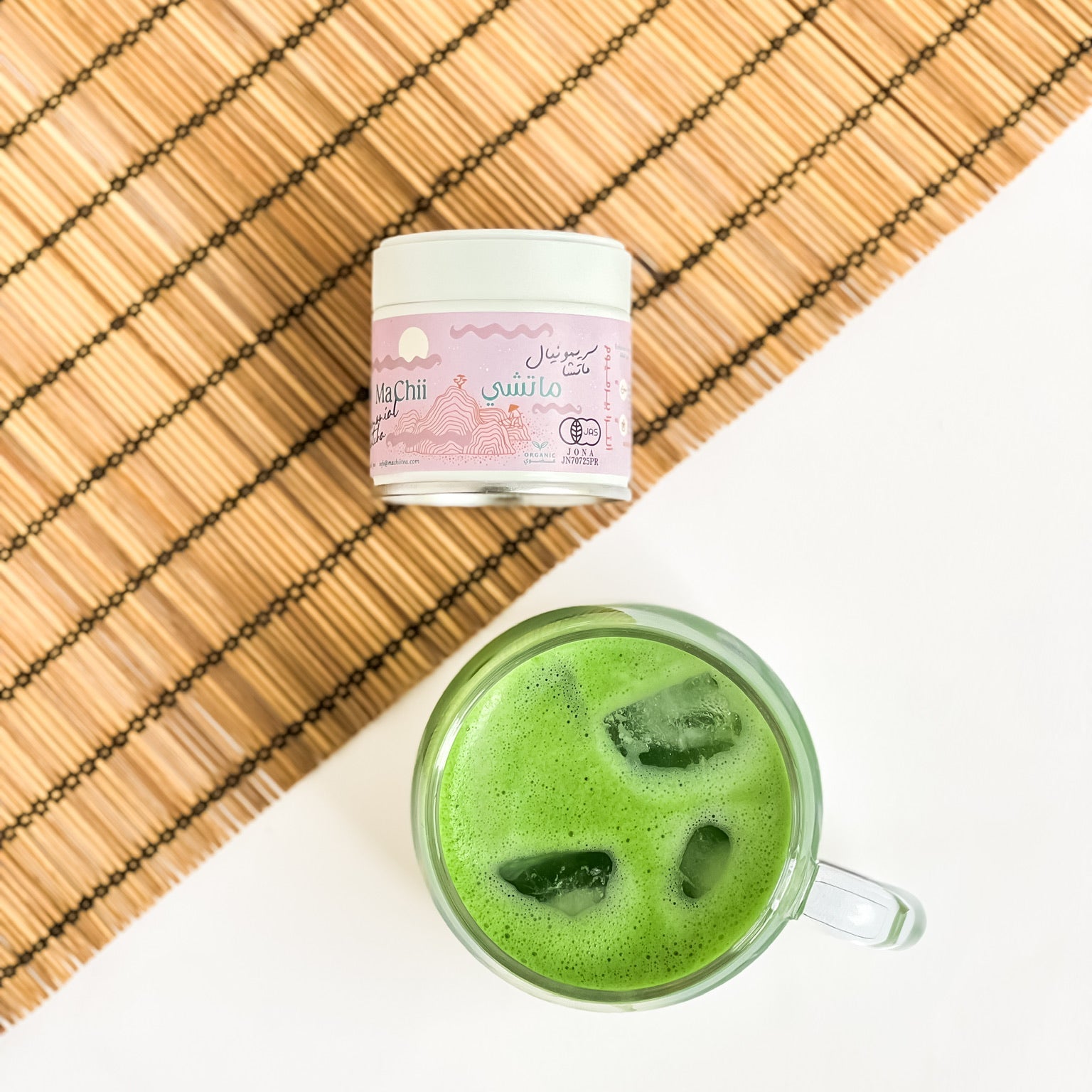 ceremonial matcha organic pink tin next to a cup of iced matcha. 